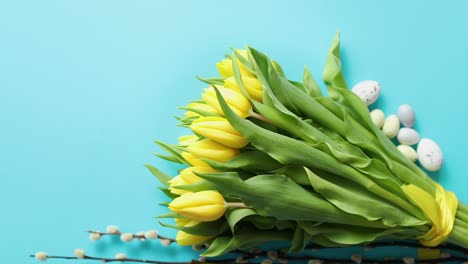 Holiday-contept-decoration-with-easter-eggs-and-yellow-tulips-over-blue