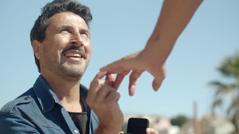 close-up shot of guy putting engagement ring on lover's finger