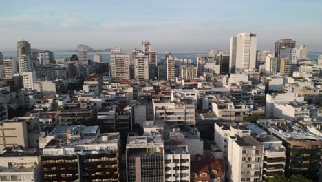 inclinación aérea hacia abajo del barrio de ipanema en rio de janeiro con edificios de gran altura y de baja altura que revelan coches que pasan en primer plano al amanecer