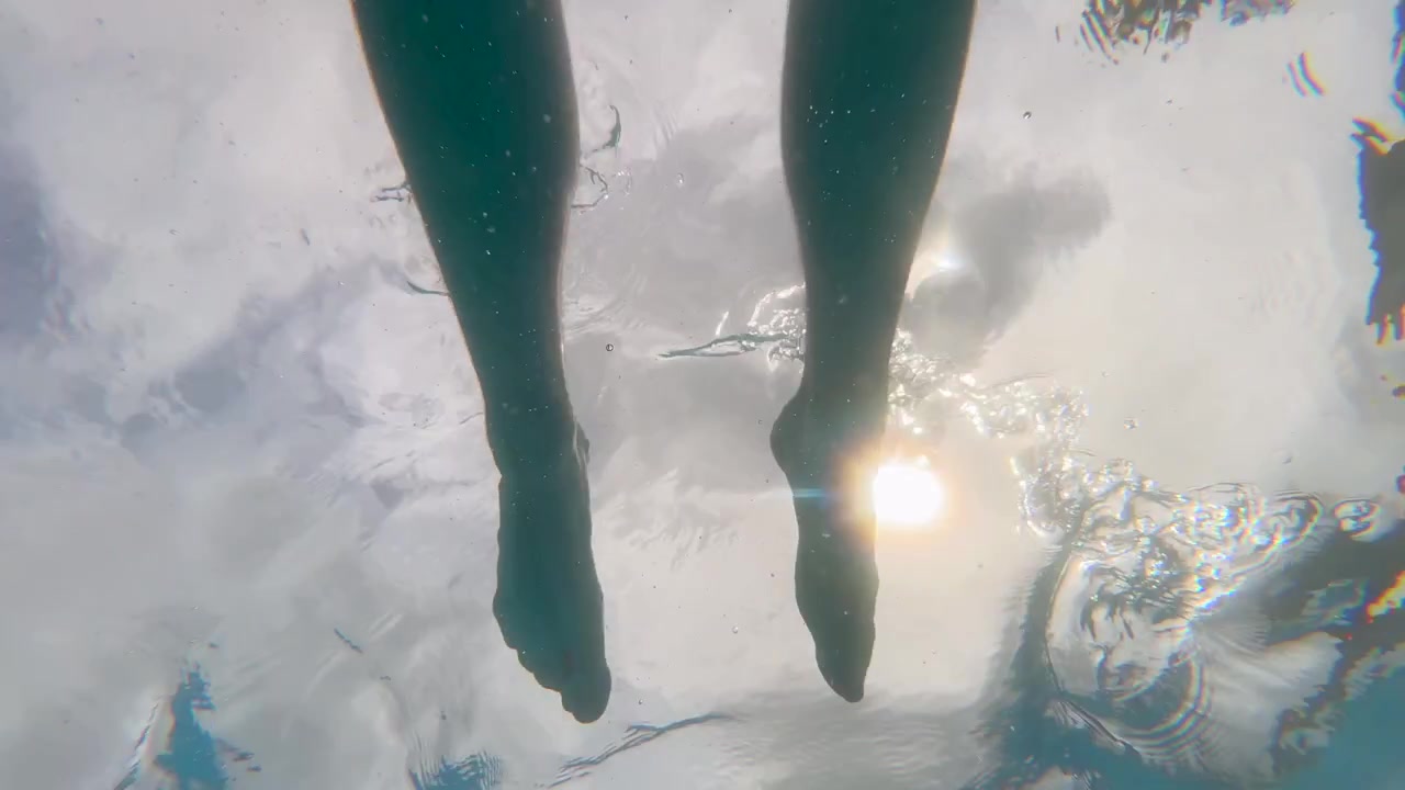 Man Swimming Underwater Looking Up at the Sun