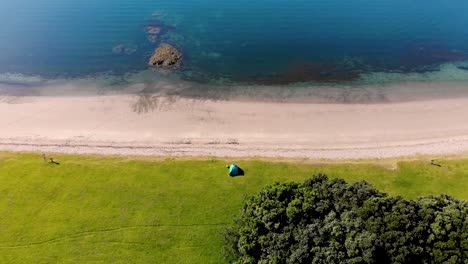 tent close to the sandy beach aerial reveal of beautiful scenic coastal scenery, summer sunny day at bay of islands, new zealand