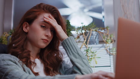 a young caucasian woman is working from home on her laptop, disappointed