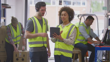 trabajadores masculinos y femeninos que usan auriculares en el almacén de distribución logística utilizando una tableta digital