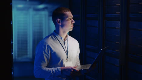 a young man works in a data center with databases and tests equipment