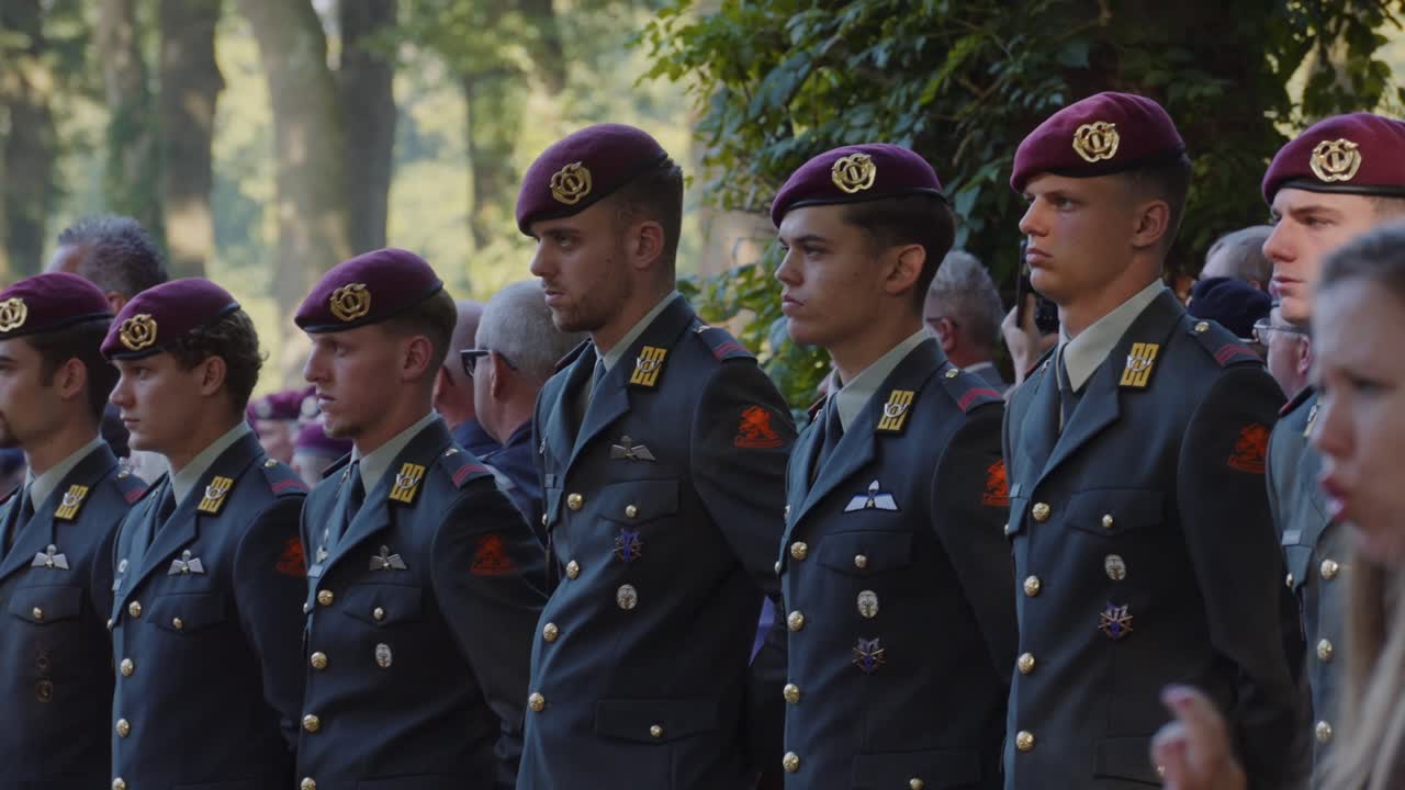 Poignant moment of conversation between security guard and employee in foreground, while soldiers in ceremonial uniforms stand in the background, reflecting the significance of the location and event
