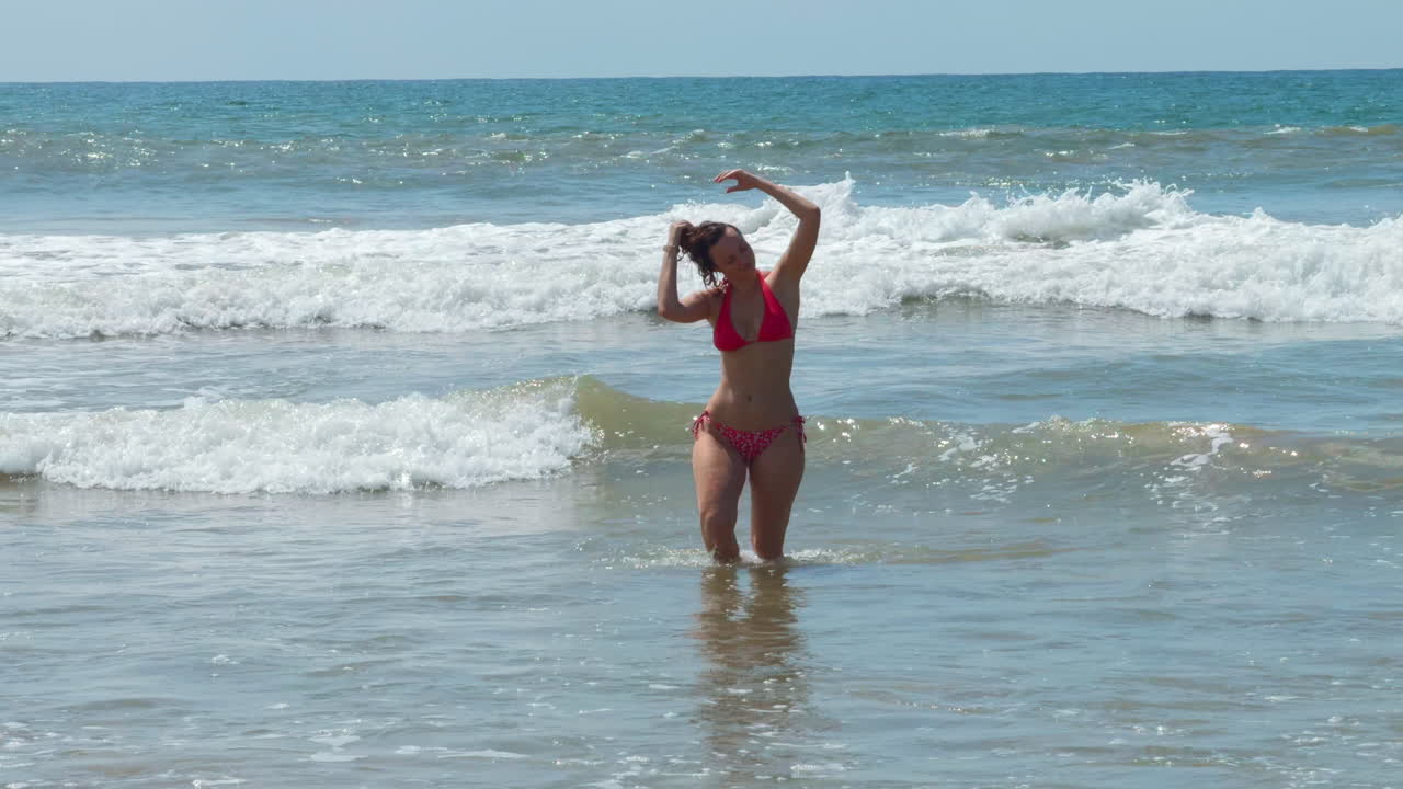 mujer en un bikini rojo disfrutando de las olas del océano