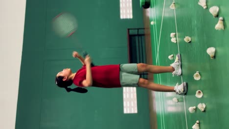 vertical footage of asian child girl practicing badminton by hitting the air with forehand swing