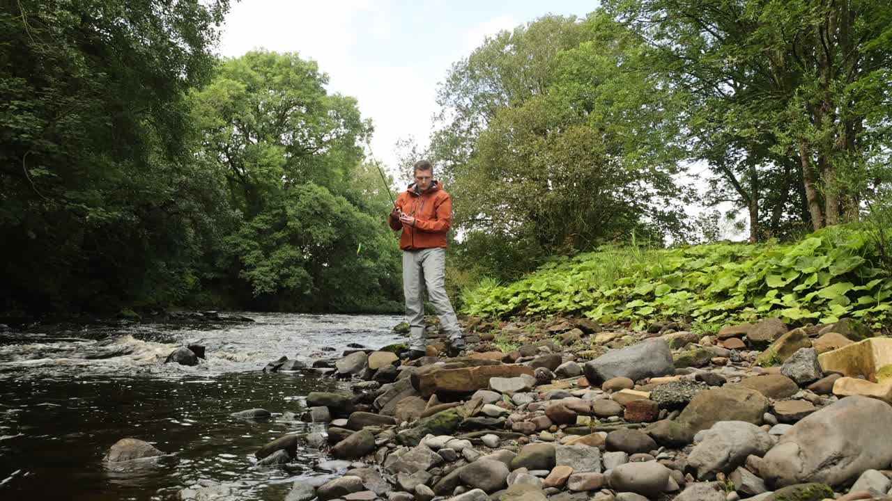 disparo de bajo ángulo de un pescador lanzando su señuelo giratorio en un río de flujo rápido