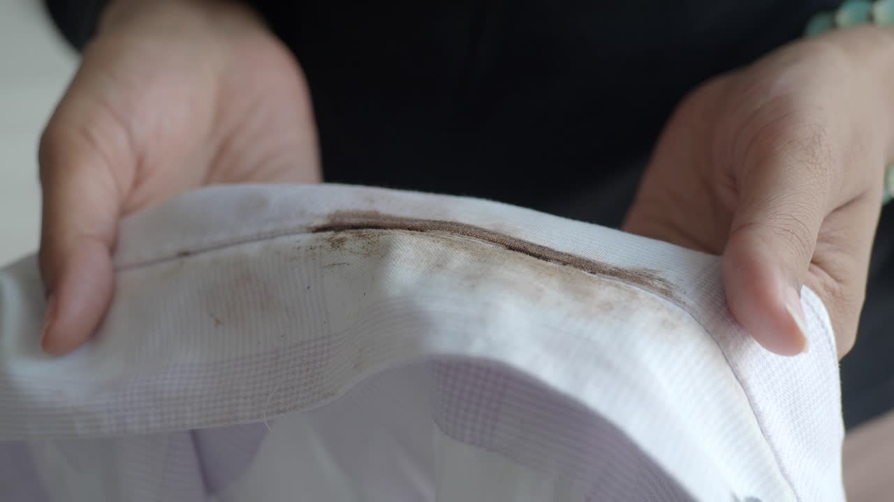 얼룩진 셔츠를 들고 있는 여자의 손을 가까이 들고