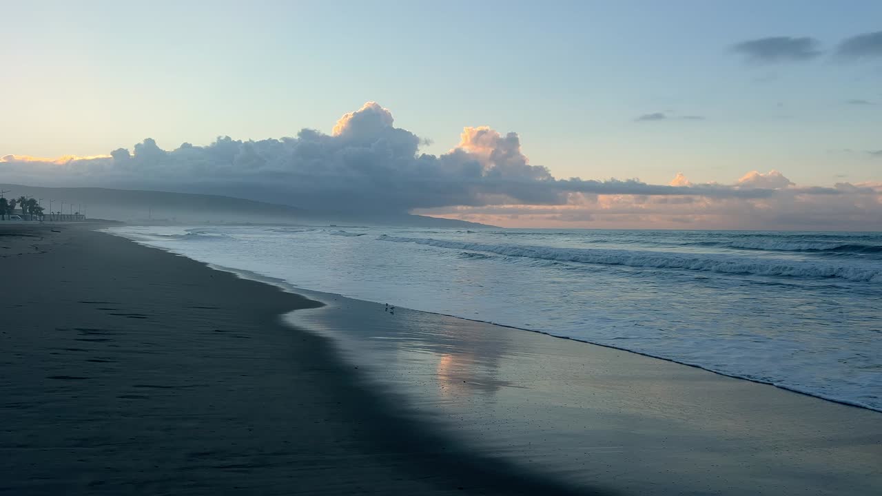 View of the waves on the shore at sunset with two birds taking flight