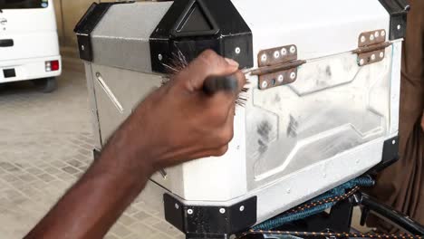 close up shot of man cleaning storage of the motorbike