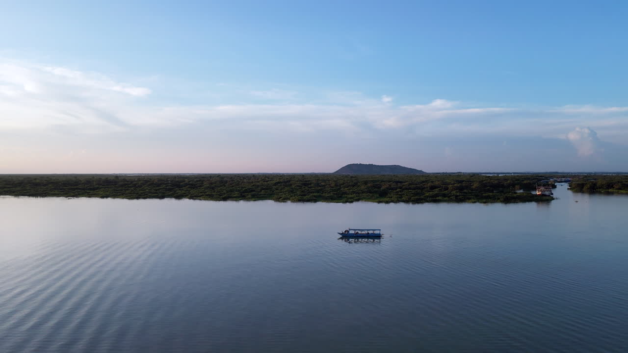un barco de chatarra en un lago en camboya al atardecer.