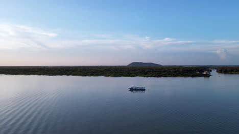 un barco de chatarra en un lago en camboya al atardecer.