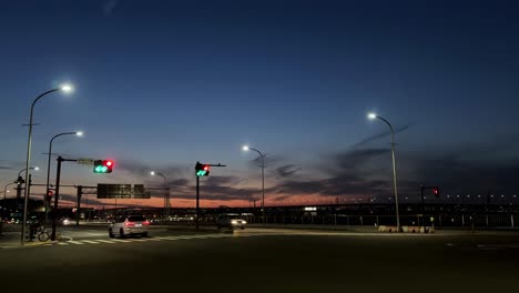 Twilight-cityscape-with-traffic-lights-and-empty-roads,-vibrant-sunset-sky-in-the-background