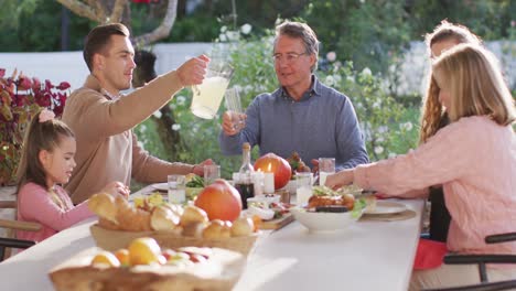 video of happy caucasian parents, daughter and grandparents serving food and drinks at outdoor table