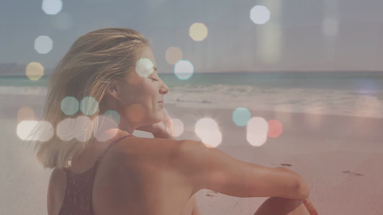 Donna che respira profondamente e cambia posizione in spiaggia, con un effetto bokeh che le fluttua intorno per il benessere