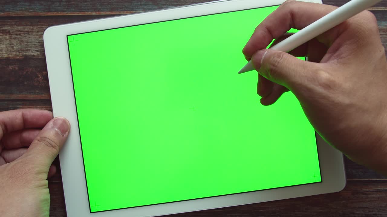 무선 스타일러스 펜으로 녹색 화면 크로마 키 태블릿 디스플레이에 글을 쓰는 사람