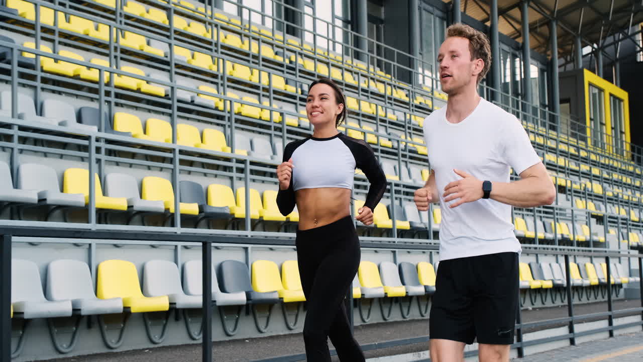 Happy sportive couple talking and running together in the stadium