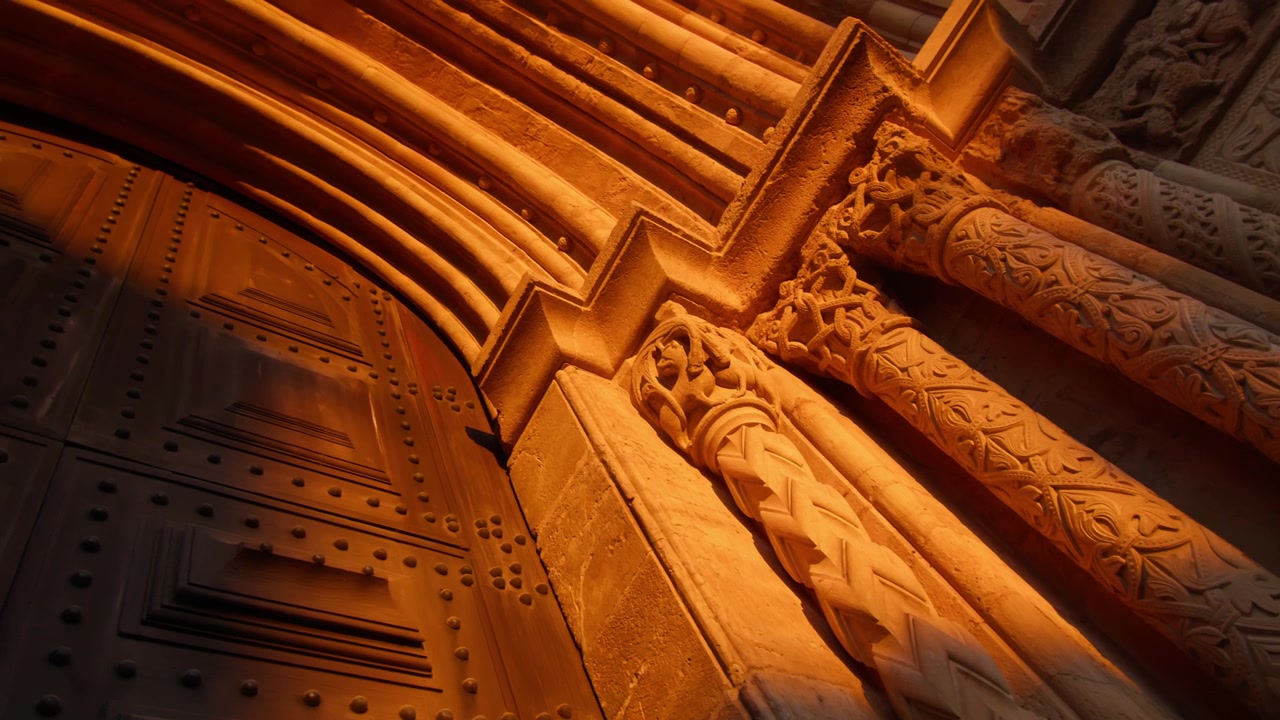 Panorámica de una enorme puerta de iglesia histórica en Coimbra, iluminada por un brillante atardecer amarillo