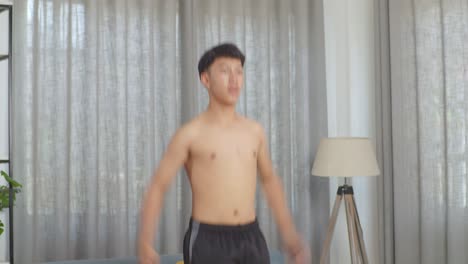 asian teenager boy doing jumping jacks with claps during the shirtless workout at home