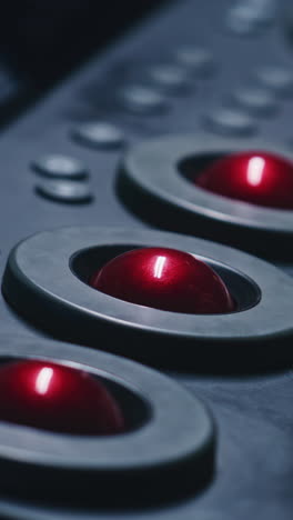 close-up view of trackballs and a hand using them on a control panel.