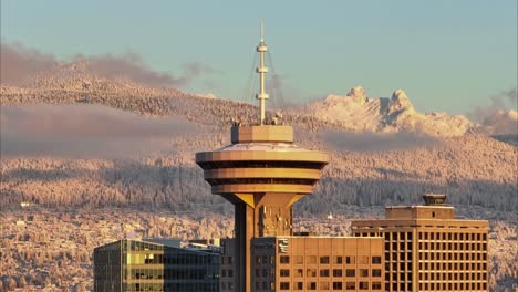 vancouver harbour centre nahaufnahme drohnen-luftaufnahme mit sonnenuntergangslicht und fernen schneebergen