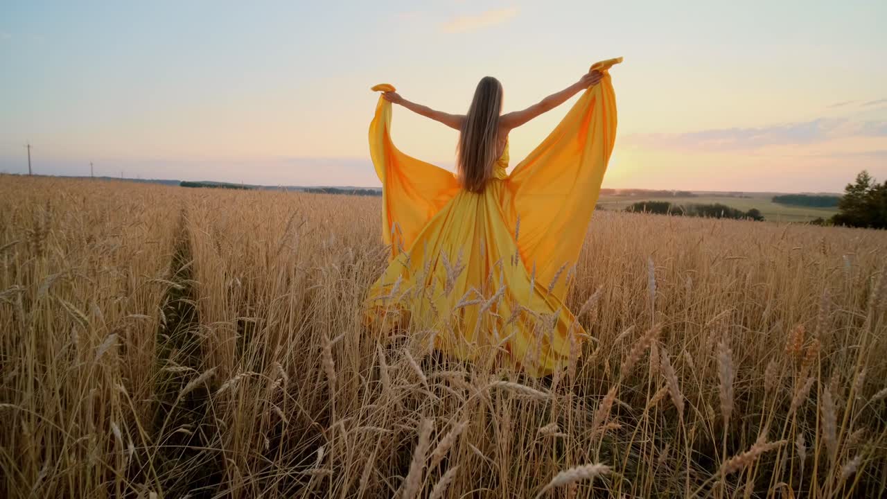 Woman in Yellow Dress in a Golden Wheat Field at Sunset