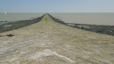 Stroll-to-warning-sign-breakwater-on-sunny-low-tide-day,-Harwich