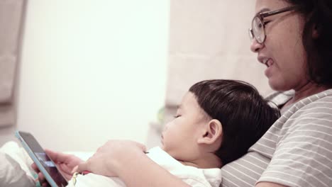 asian baby using mobile phones with mom on the bed