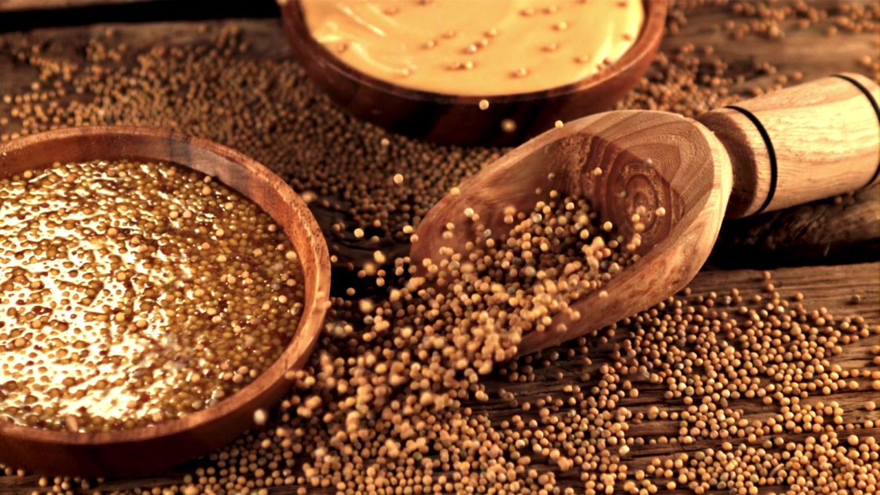 Mustard Seeds Pouring from Wooden Scoop with Prepared Mustard