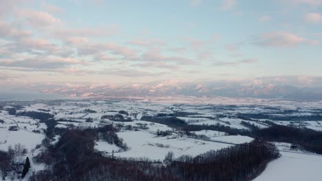 Snow-covered-landscape-in-Iwanai,-Hokkaido-with-mountain-views-during-winter-at-sunrise