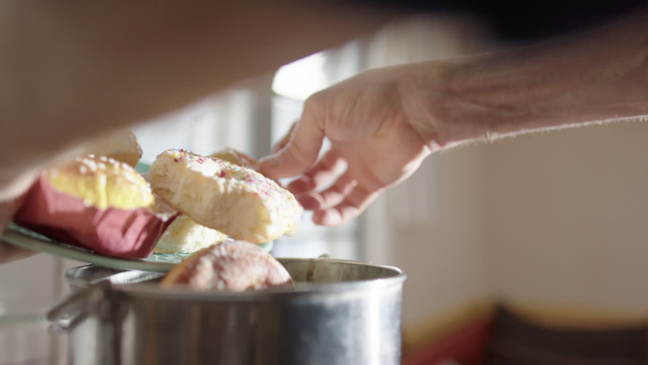 Closeup view of excess buns and donuts being dumped into metal composting bin