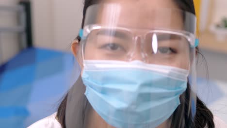 portrait of an asia young female who is wearing a face shield with mask rounded around her face from a frontal perspective to protect her glasses and eyes, scene of slow motion