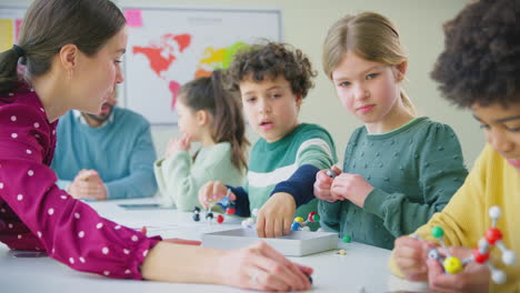 multi-cultural students with teachers in classroom studying molecular model in science class