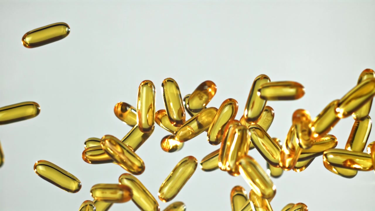 Capsule dorate di Omega-3 che cadono al rallentatore