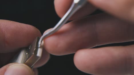 man cleans usb plug with metal hook on black background