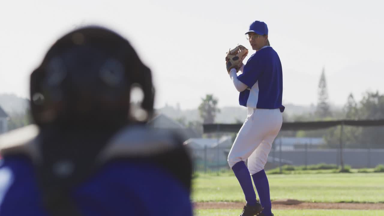 Giocatrice di baseball caucasica con gli occhiali che lancia la palla su un campo da baseball.