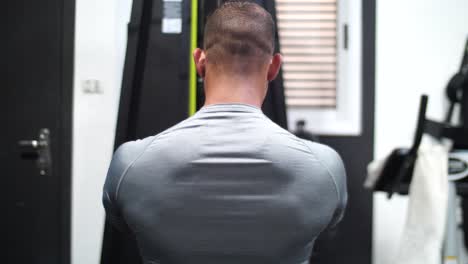 a muscular bodybuilder, passionately working out at the gym, lifts weights the camera is from his back side