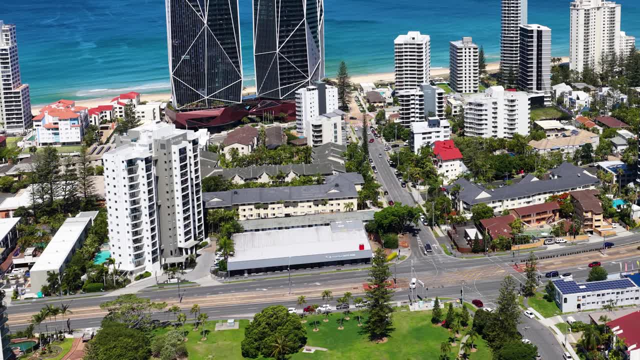 Daytime drone ascends above Broadbeach Waters, revealing high-rise buildings, coastline, and blue ocean