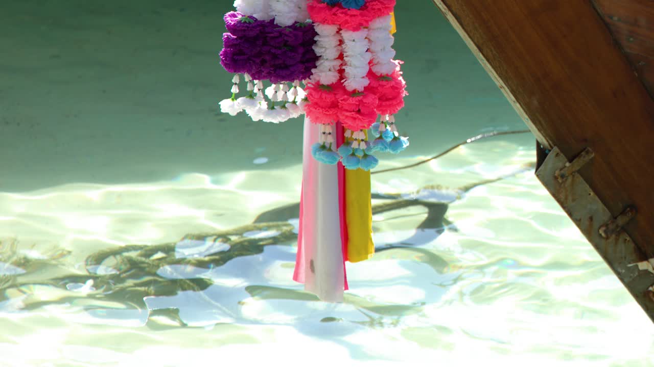 Primer plano de vibrantes decoraciones florales en una embarcación de madera sobre agua tropical clara y turquesa