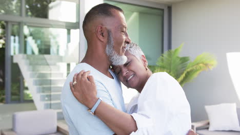 biracial couple embraces lovingly outside a modern home