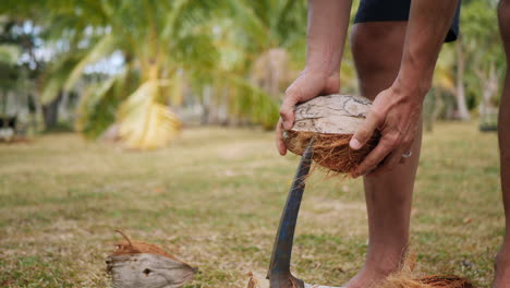 Primer-Plano-Del-Hombre-Quitando-La-Capa-Exterior-Dura-De-Coco-Fresco-En-La-Espiga-De-Hierro