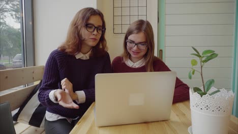 dos mujeres jóvenes trabajando juntas en una computadora portátil en un café