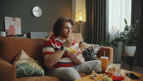 man eating chips on couch