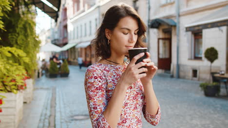 Caucasian-woman-enjoying-drinking-morning-coffee-hot-drink,-relaxing,-taking-a-break-in-city-street