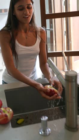 woman washing fruit in a kitchen sink