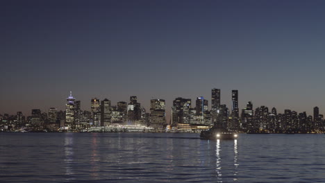 sea bus approaching lonsdale quay, vancouver skyline at dusk in background