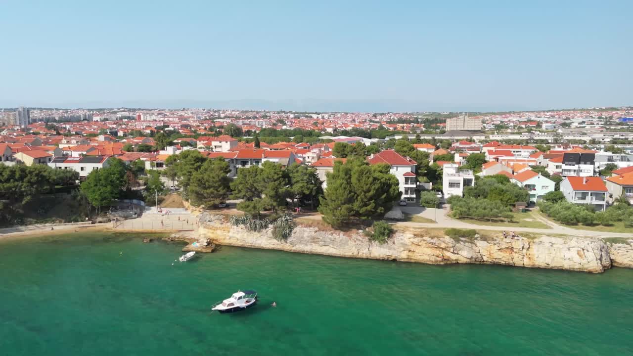 Green waters of the Adriatic, sandy cliffs, red rooftops in drone slide footage, Zadar, Croatia