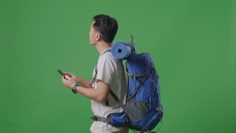 hombre con mochila y teléfono inteligente en pantalla verde