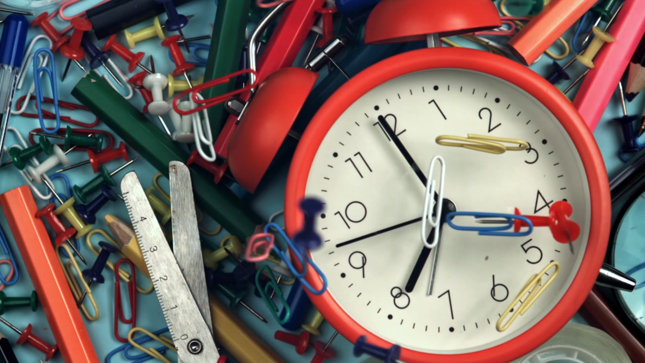 Colorful Office Supplies Falling Around an Alarm Clock